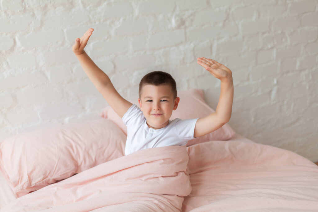 Young boy in white shirt sitting on bed