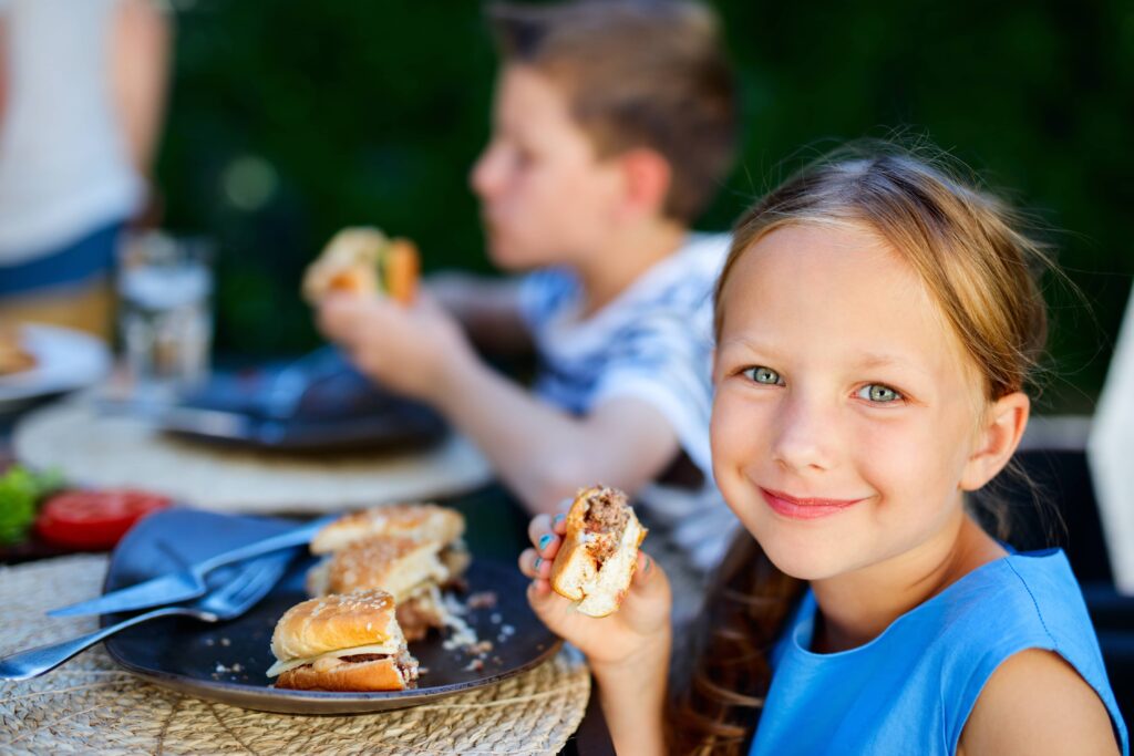 Young girl smiling and eating hamburger